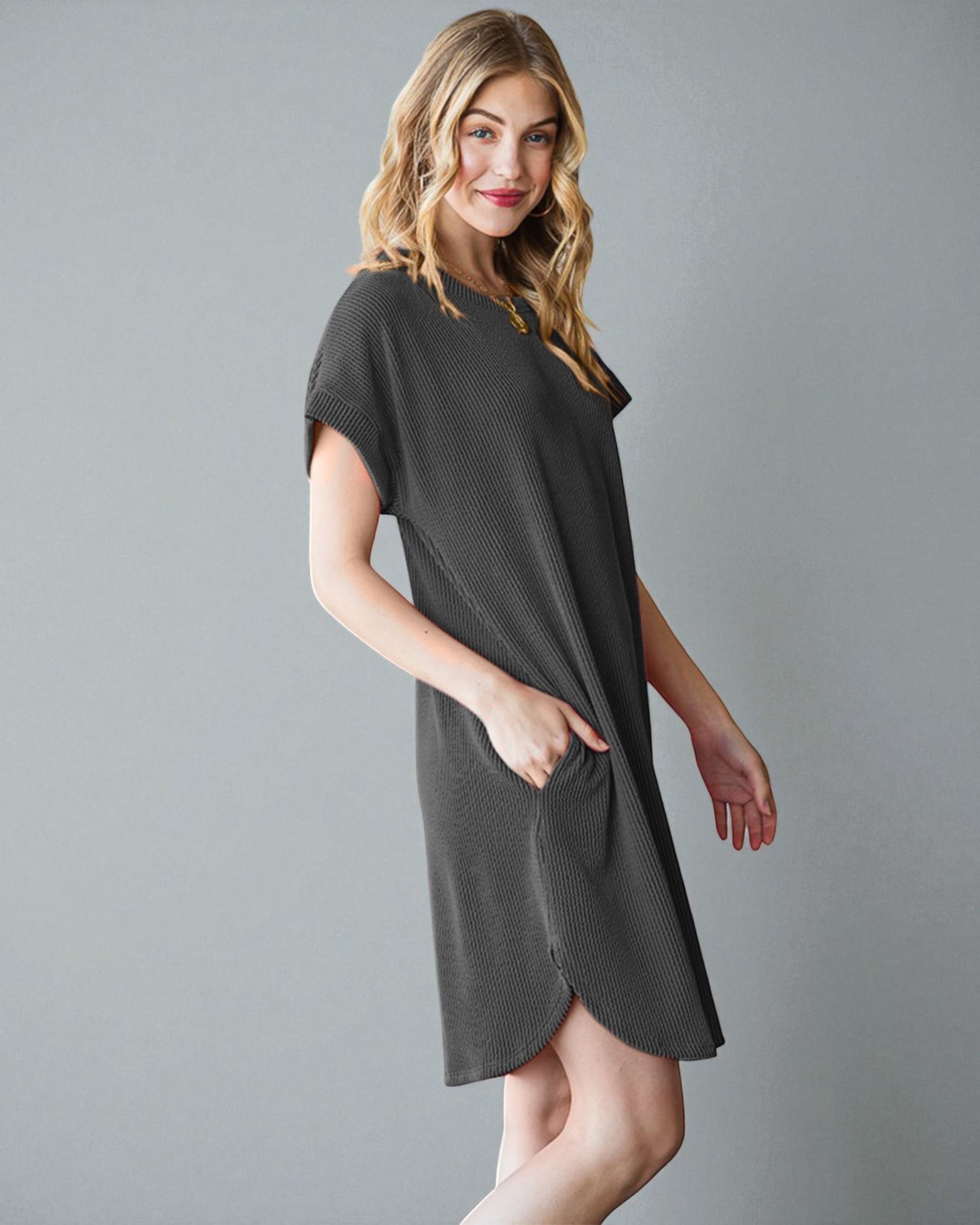 Woman wearing a dark gray dress against a plain background