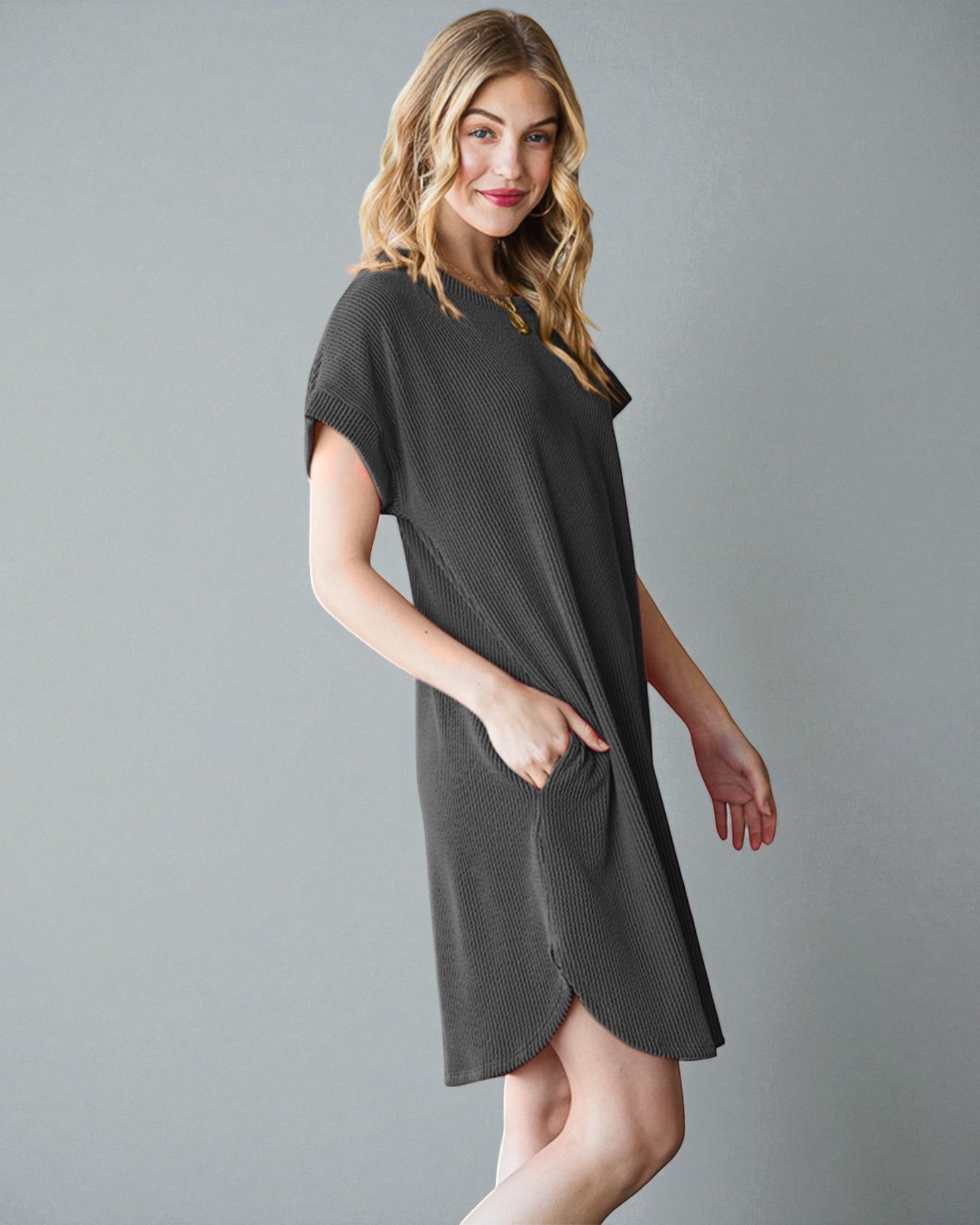 Woman wearing a dark gray dress against a plain background