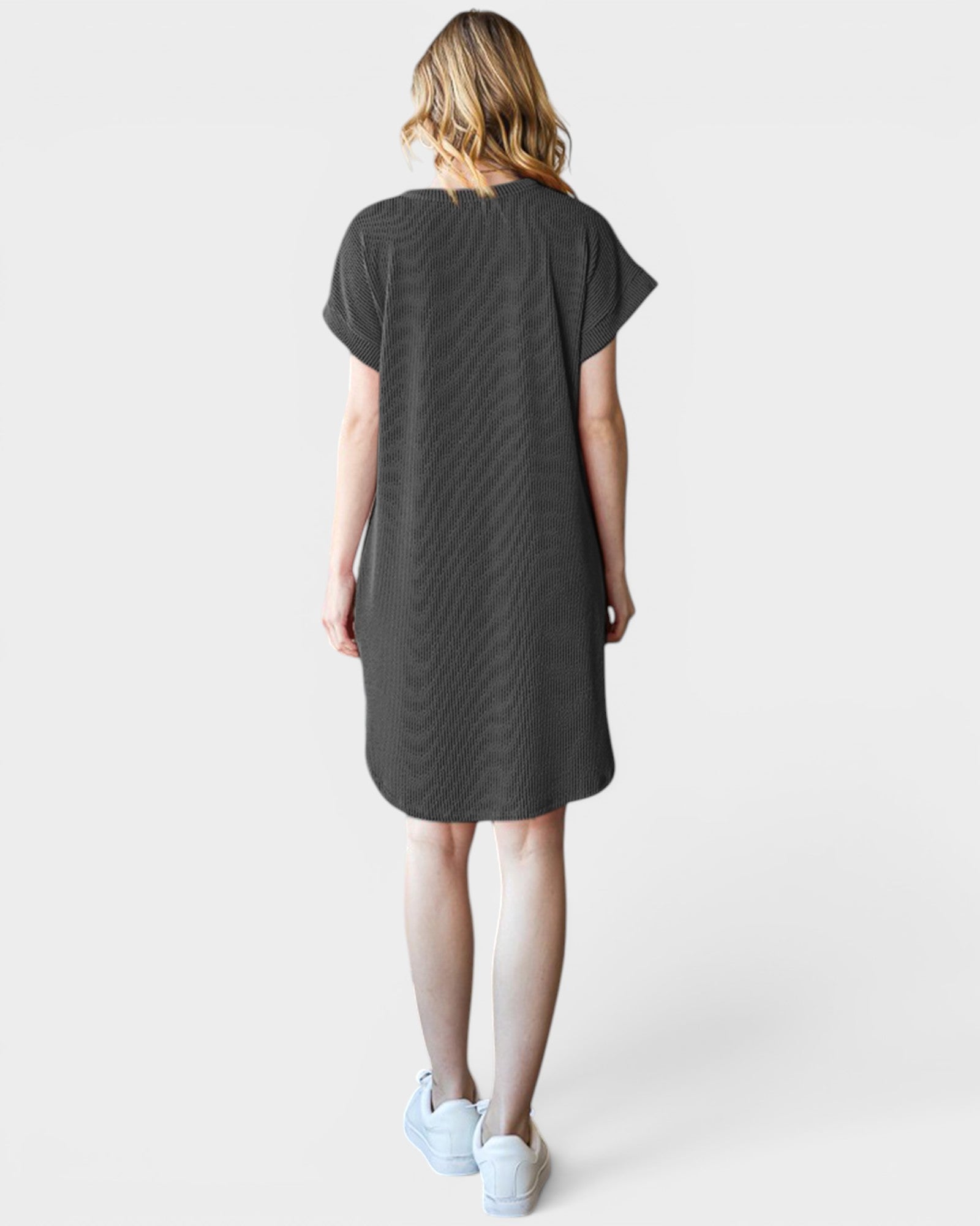 Woman wearing a dark gray t-shirt dress on a white background