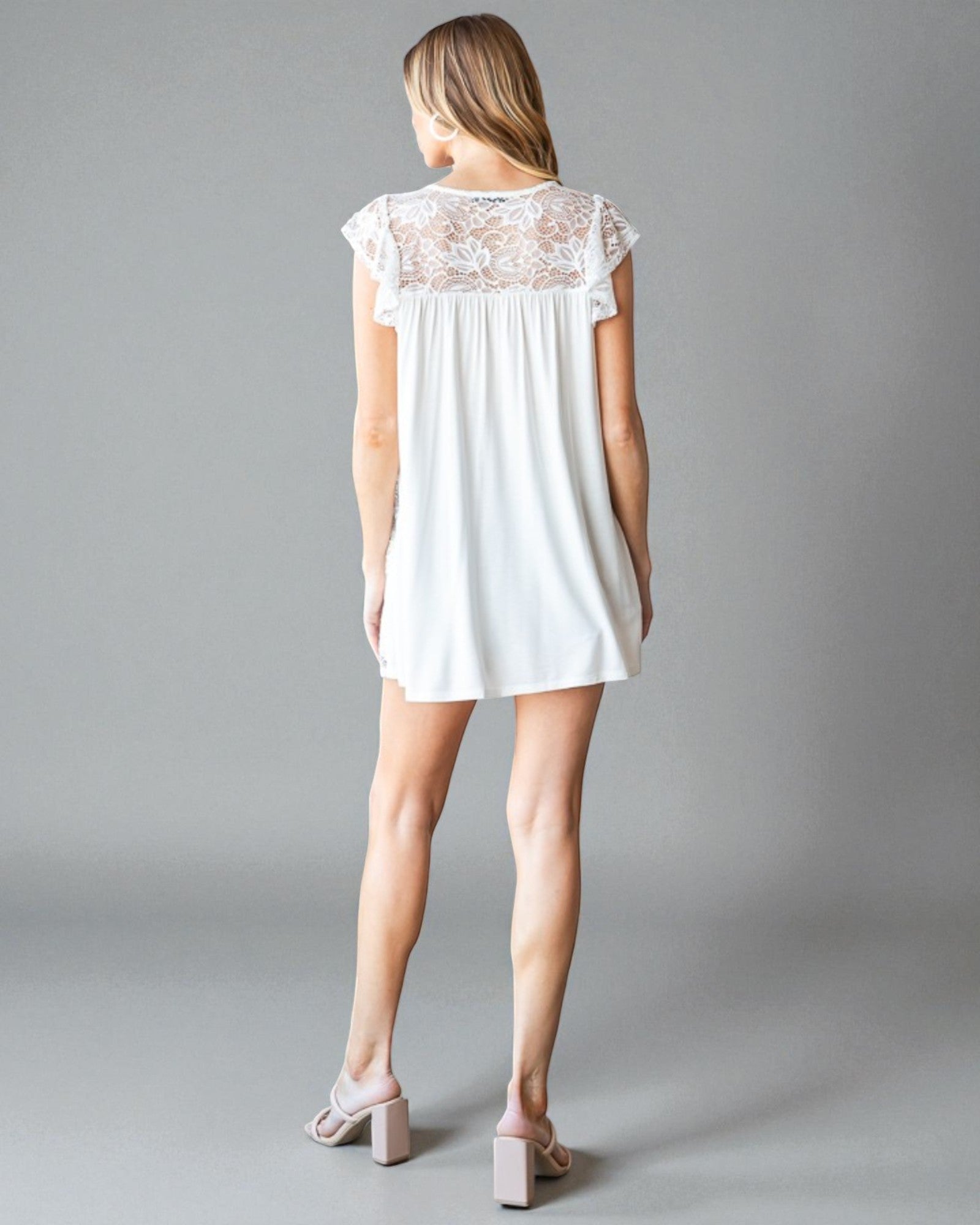 Woman wearing a white lace-trimmed dress on a gray background