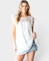 Woman wearing a white lace top and denim shorts on a plain background