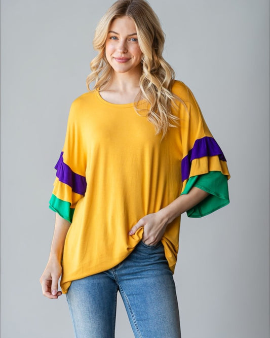 Woman wearing a yellow top with colorful sleeves against a gray background