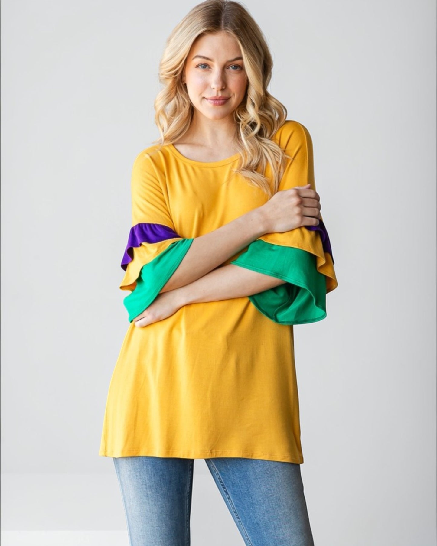 Woman wearing a yellow top with colorful sleeves on a plain background