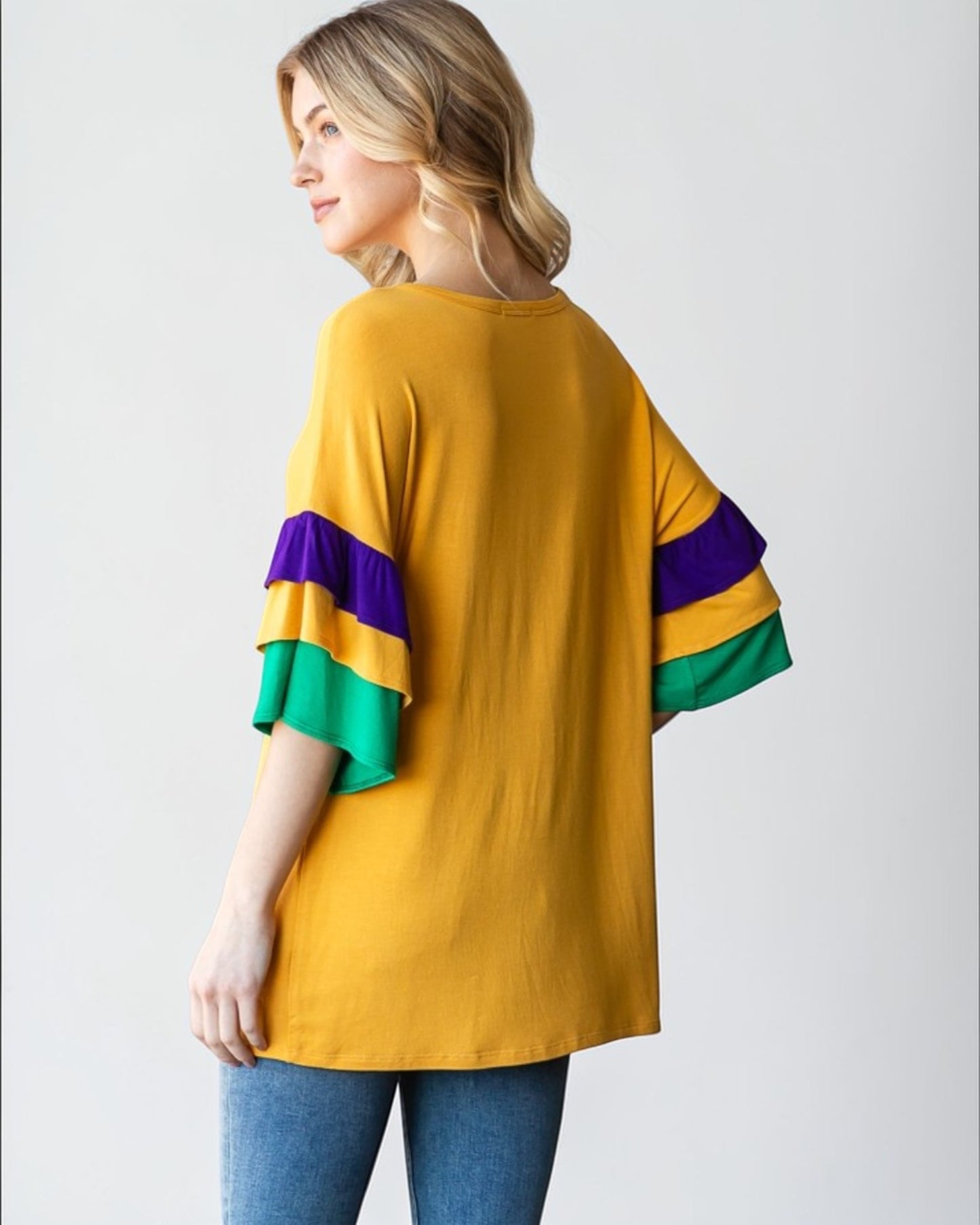 Woman wearing a mustard yellow shirt with colorful sleeves on a white background