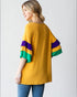Woman wearing a mustard yellow shirt with colorful sleeves on a white background