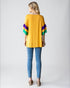 Woman wearing a yellow sweater with colorful sleeves and blue jeans on a white background