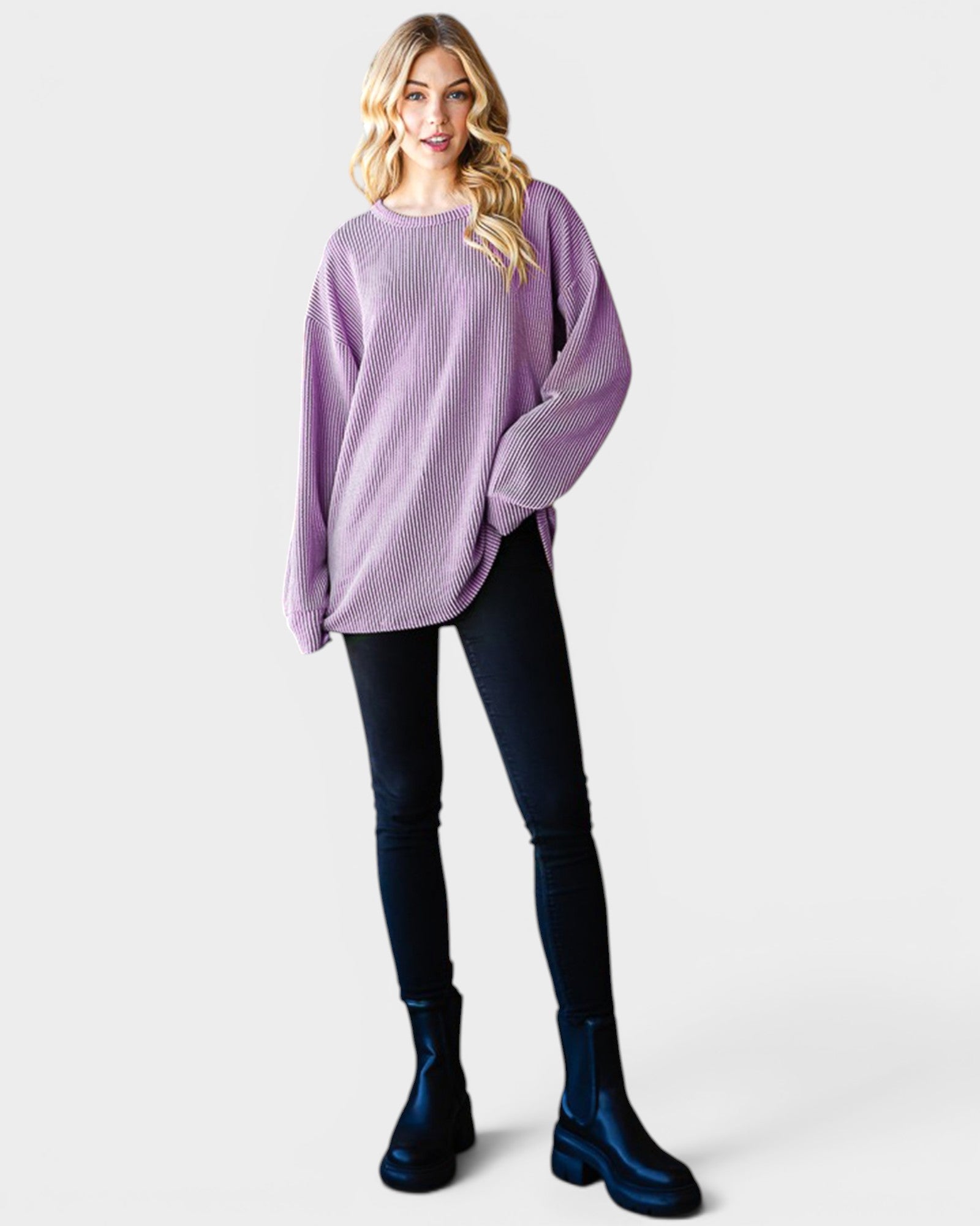 Woman wearing a purple sweater, black leggings, and blue boots on a white background