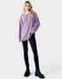 Woman wearing a purple sweater, black leggings, and blue boots on a white background