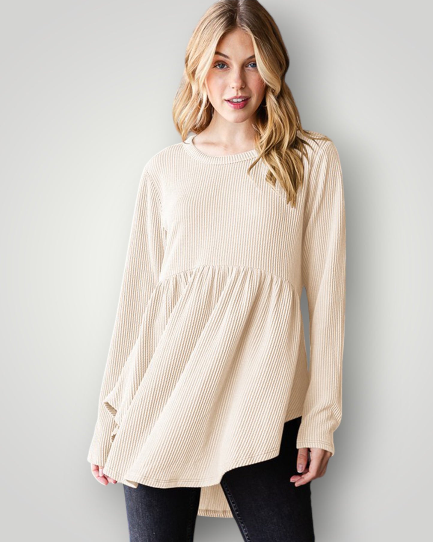 Woman wearing a beige long-sleeve top against a plain background