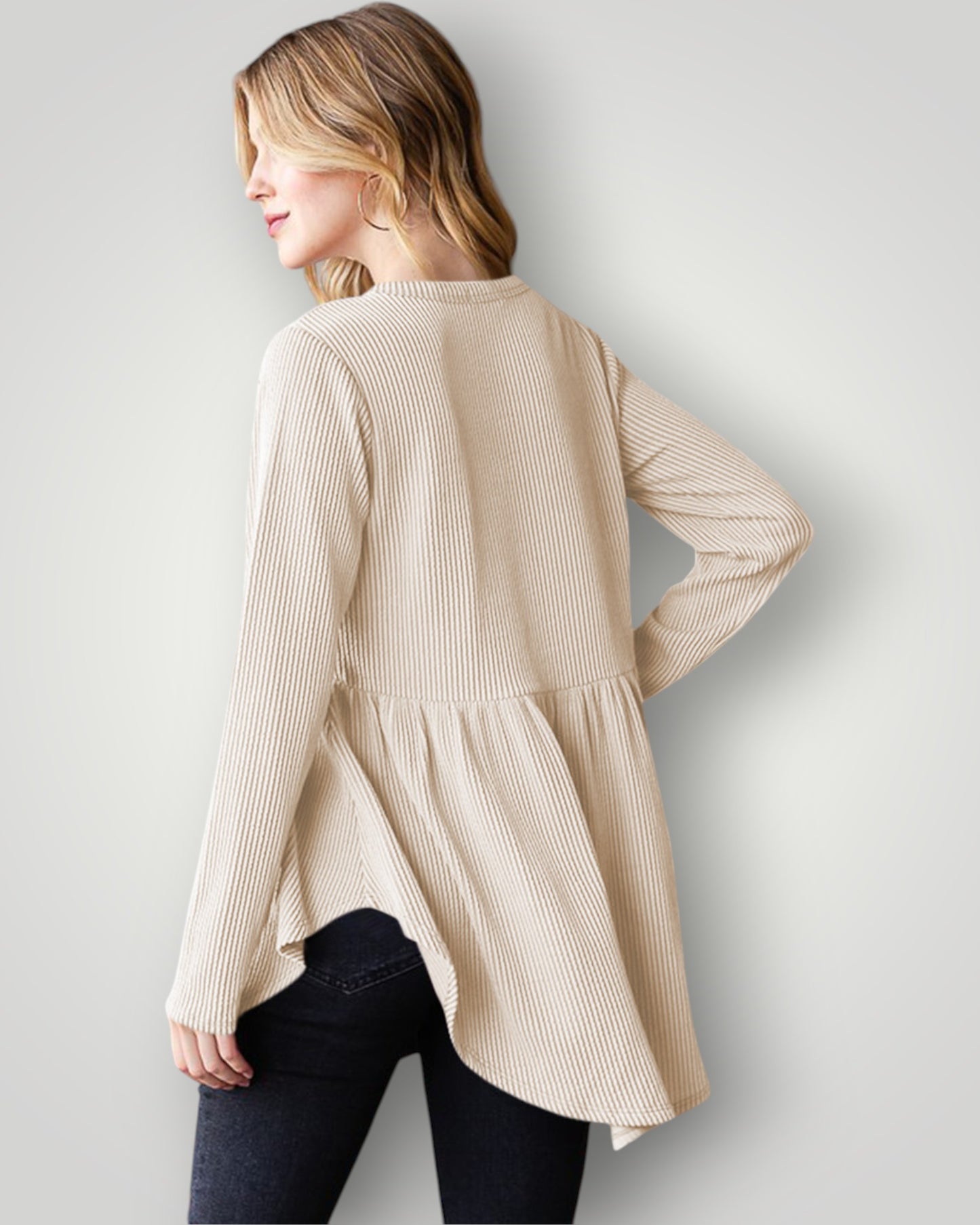 Woman wearing a beige ribbed sweater against a plain background