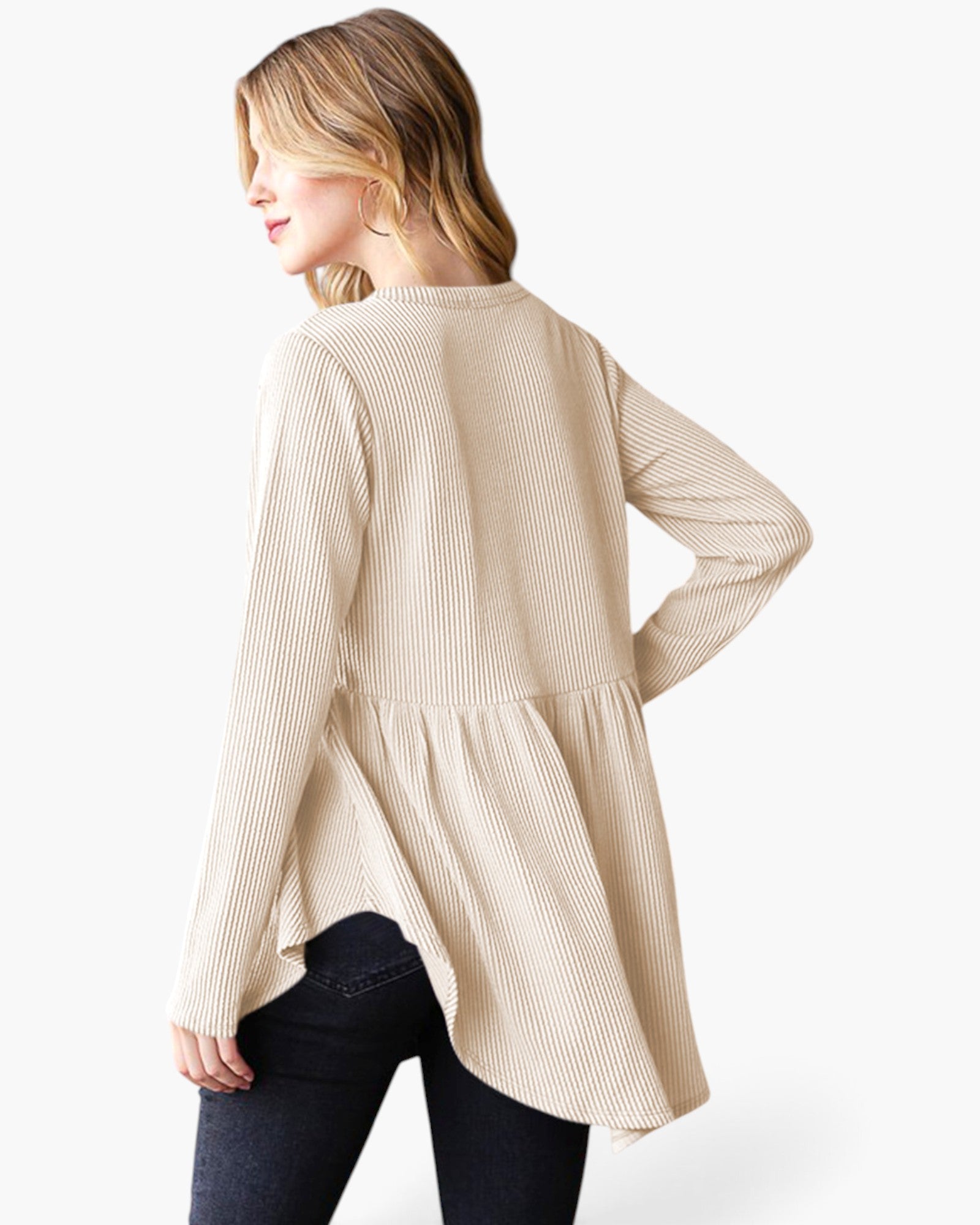 A woman wearing a beige ribbed long-sleeve tunic top with a peplum waist, shown from a three-quarter back angle against a plain white background.