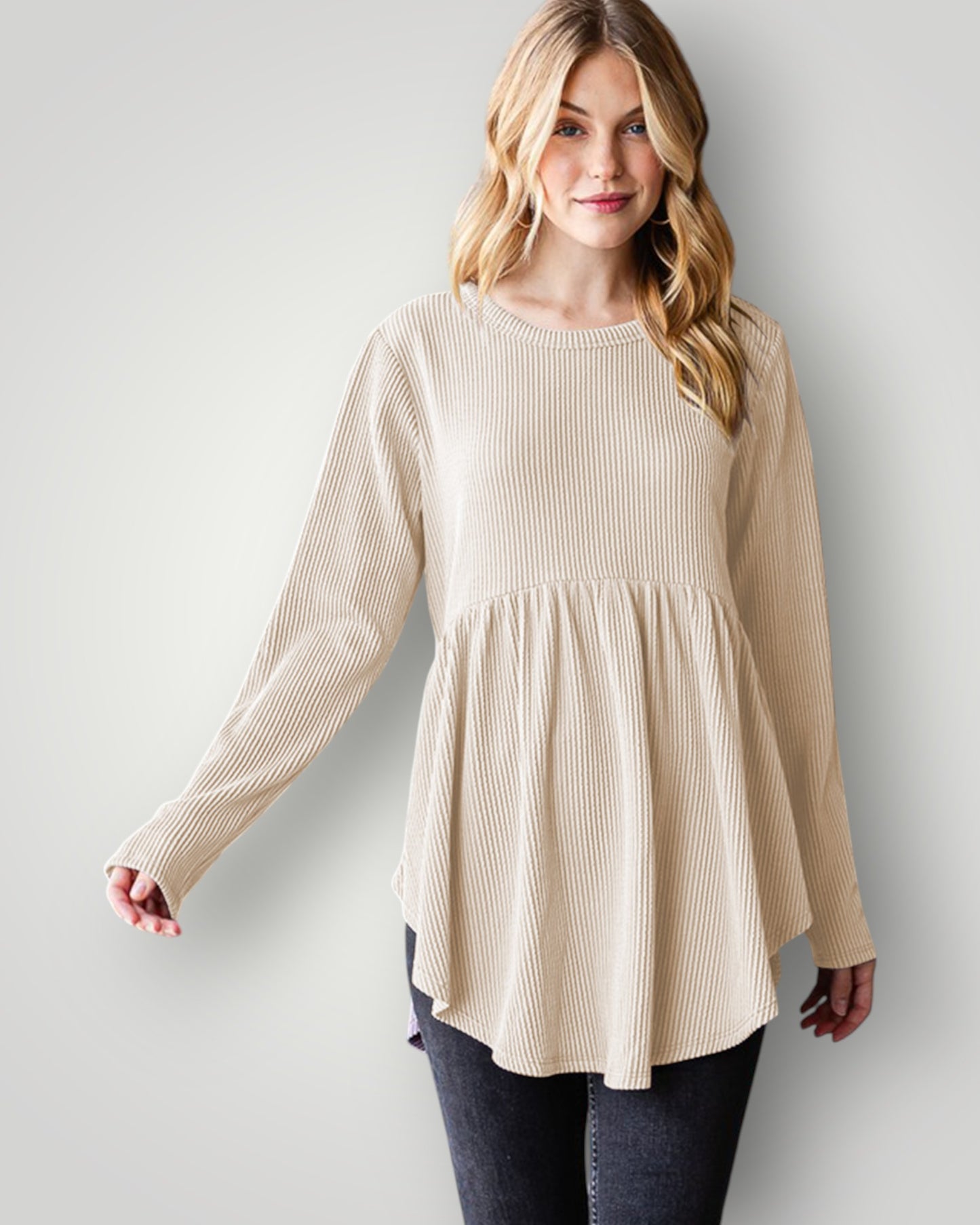 Woman wearing a beige long-sleeve top against a plain background