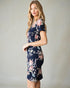 Woman wearing a navy floral dress against a plain background