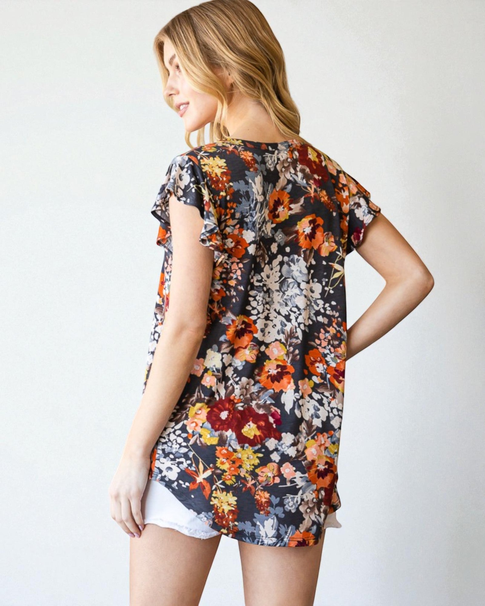 Woman wearing a floral print top with a plain background