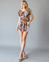 Woman wearing a floral romper on a plain background