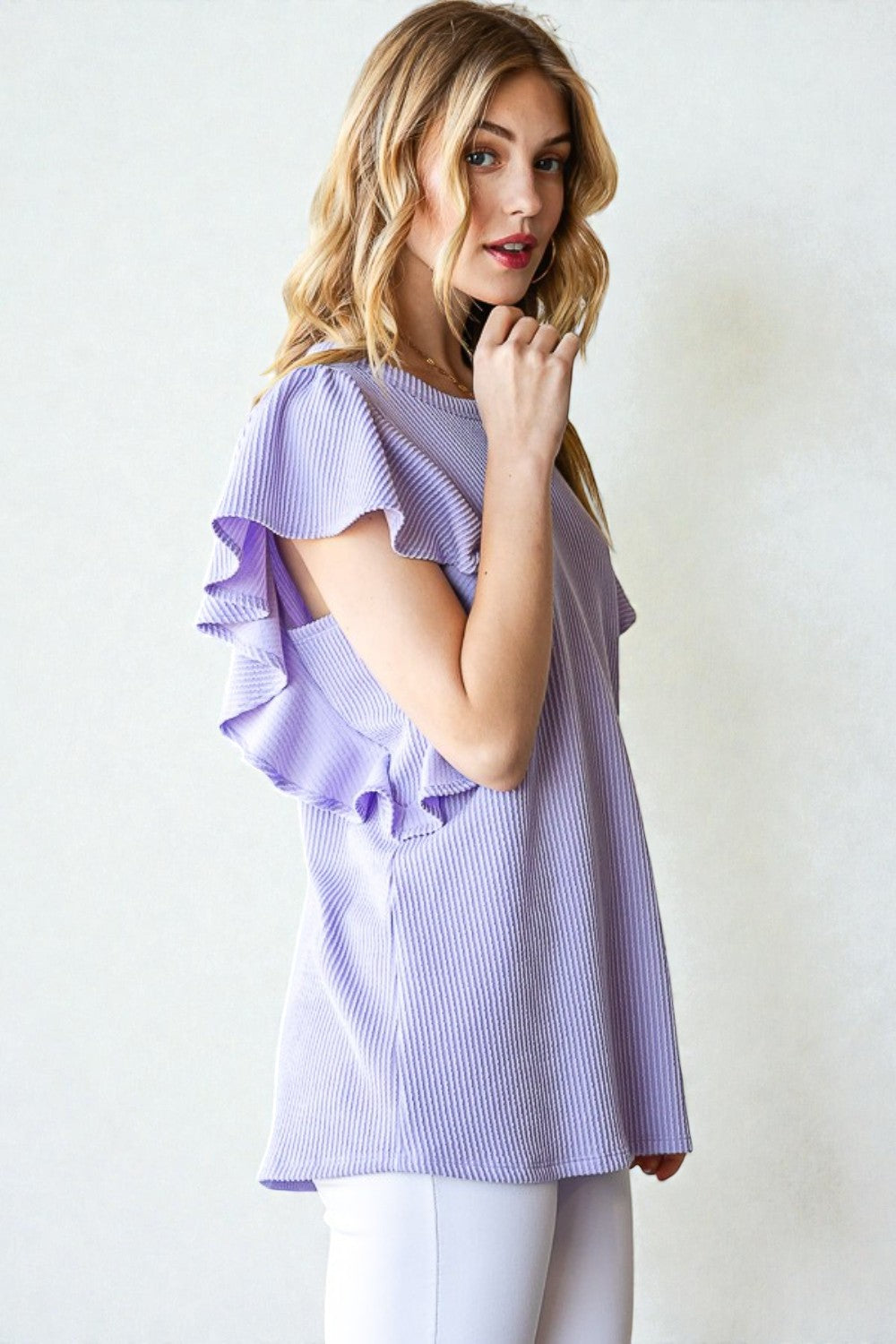 Woman wearing a light purple blouse with ruffled sleeves against a white background