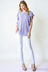 Woman wearing a light purple top and white pants against a white background