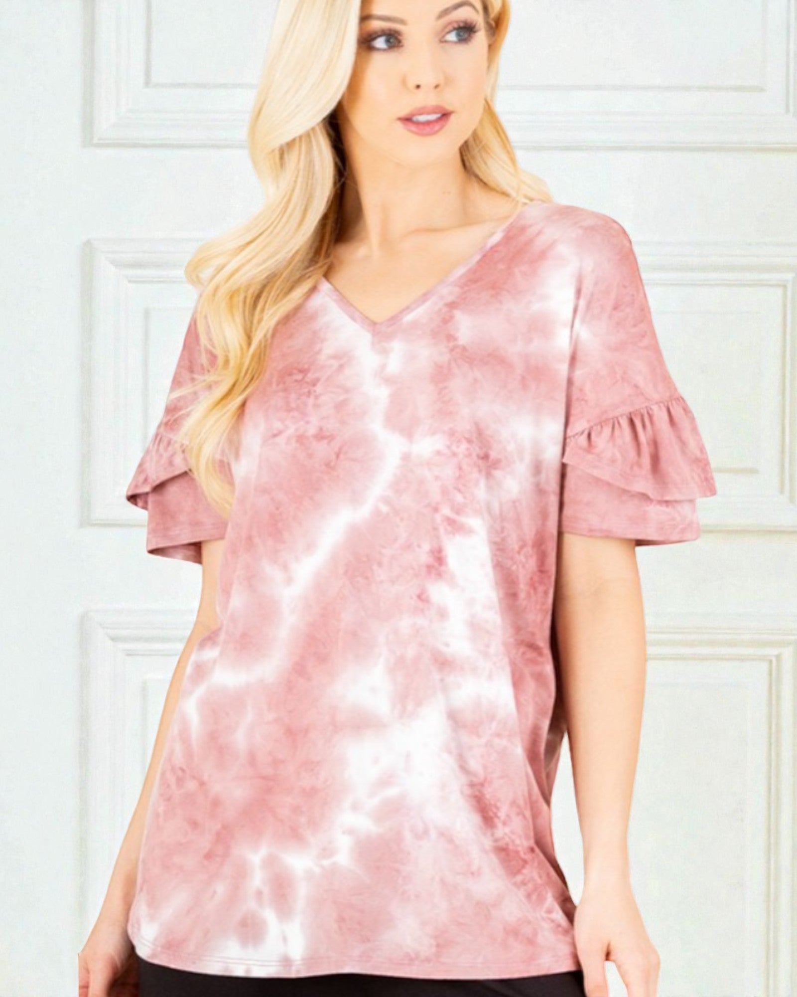 Woman wearing a pink tie-dye blouse with ruffled sleeves against a white background