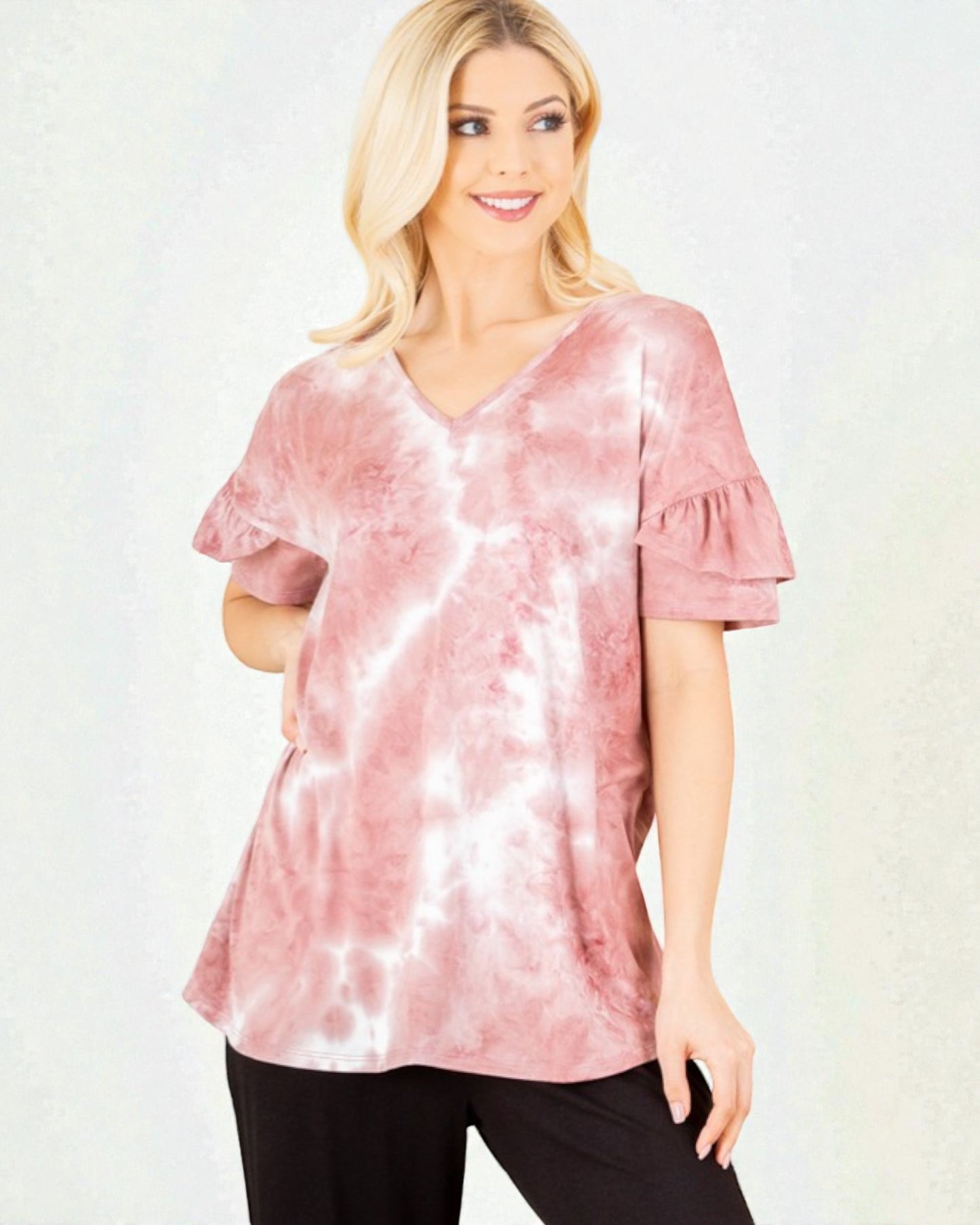 Woman wearing a pink tie-dye blouse with ruffled sleeves on a white background