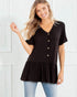 Woman wearing a black short-sleeve top with buttons and a layered skirt against a white background