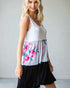 Woman wearing a sleeveless dress with floral pattern and black bottom half on a plain background