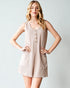 Woman wearing a beige sleeveless dress with buttons on a light gray background