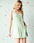Woman wearing a light green sleeveless dress with buttons on a polka dot background