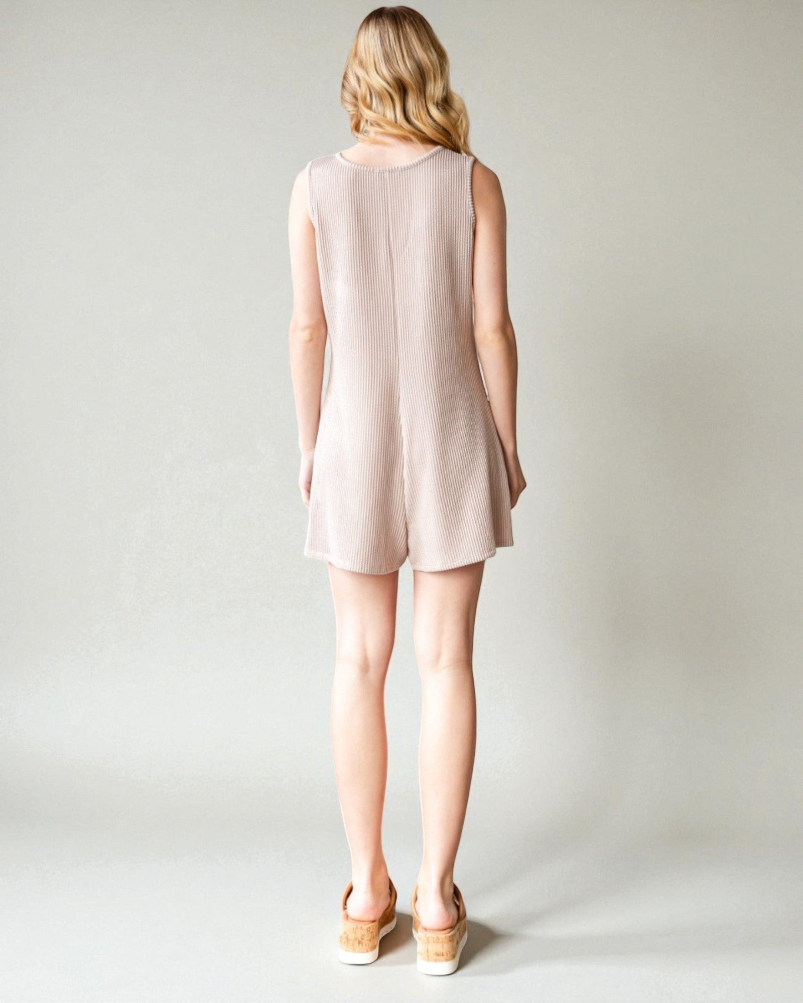 Woman wearing a light pink sleeveless dress on a plain background