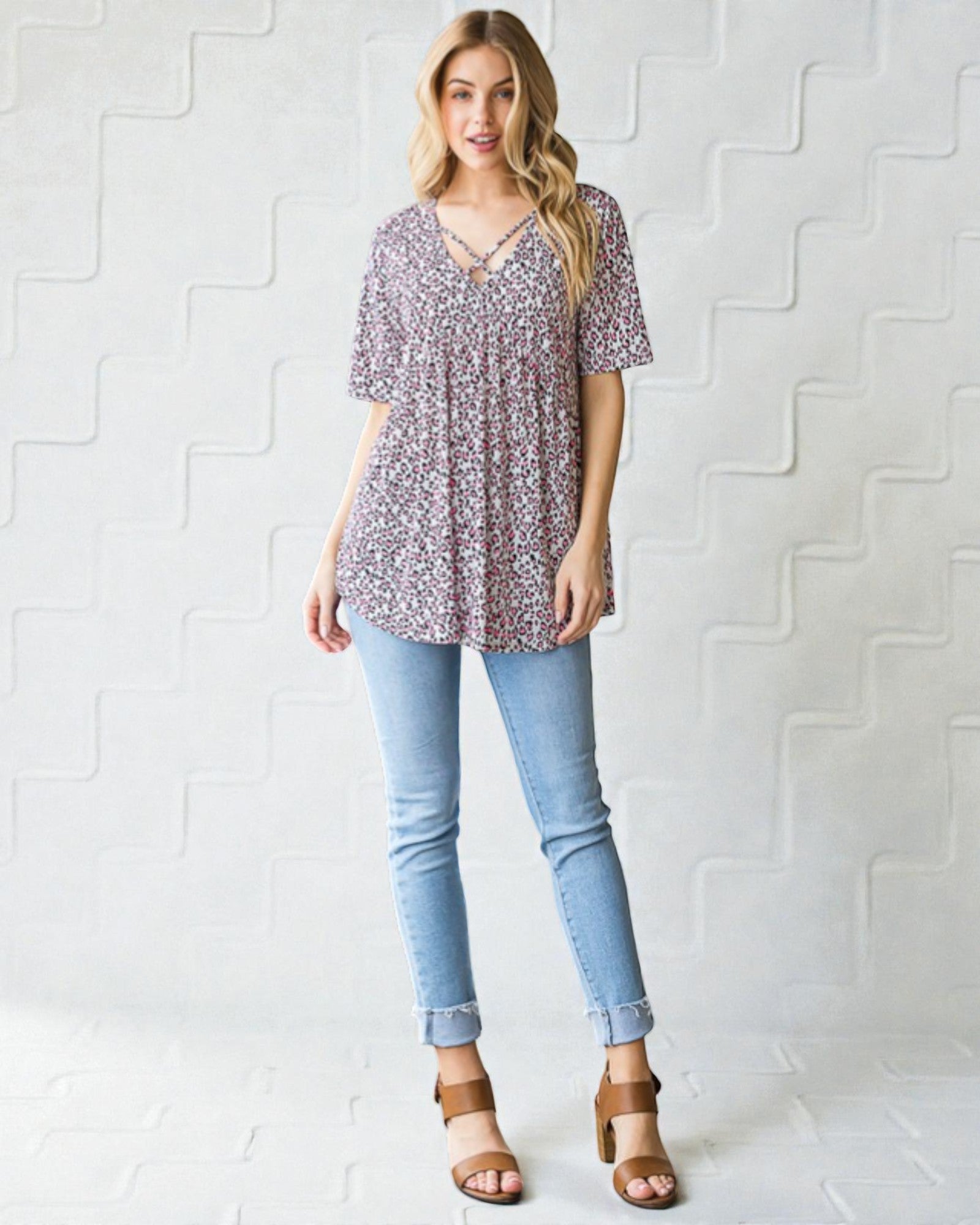 Woman wearing a floral blouse and light blue jeans against a white background