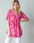Woman wearing a pink and white patterned blouse against a plain background