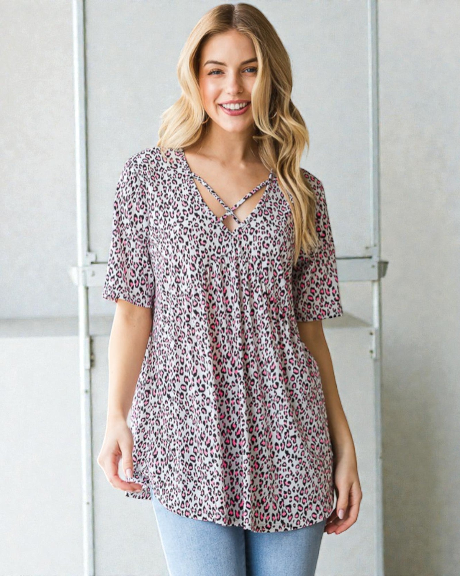 Woman wearing a patterned blouse standing against a plain background