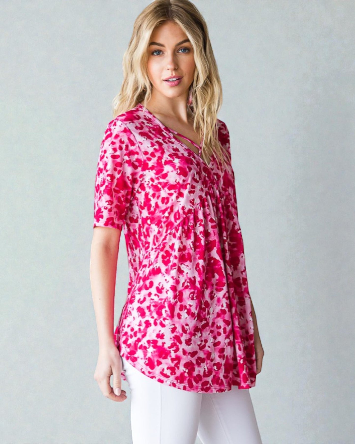 Woman wearing a pink and white patterned top against a plain background