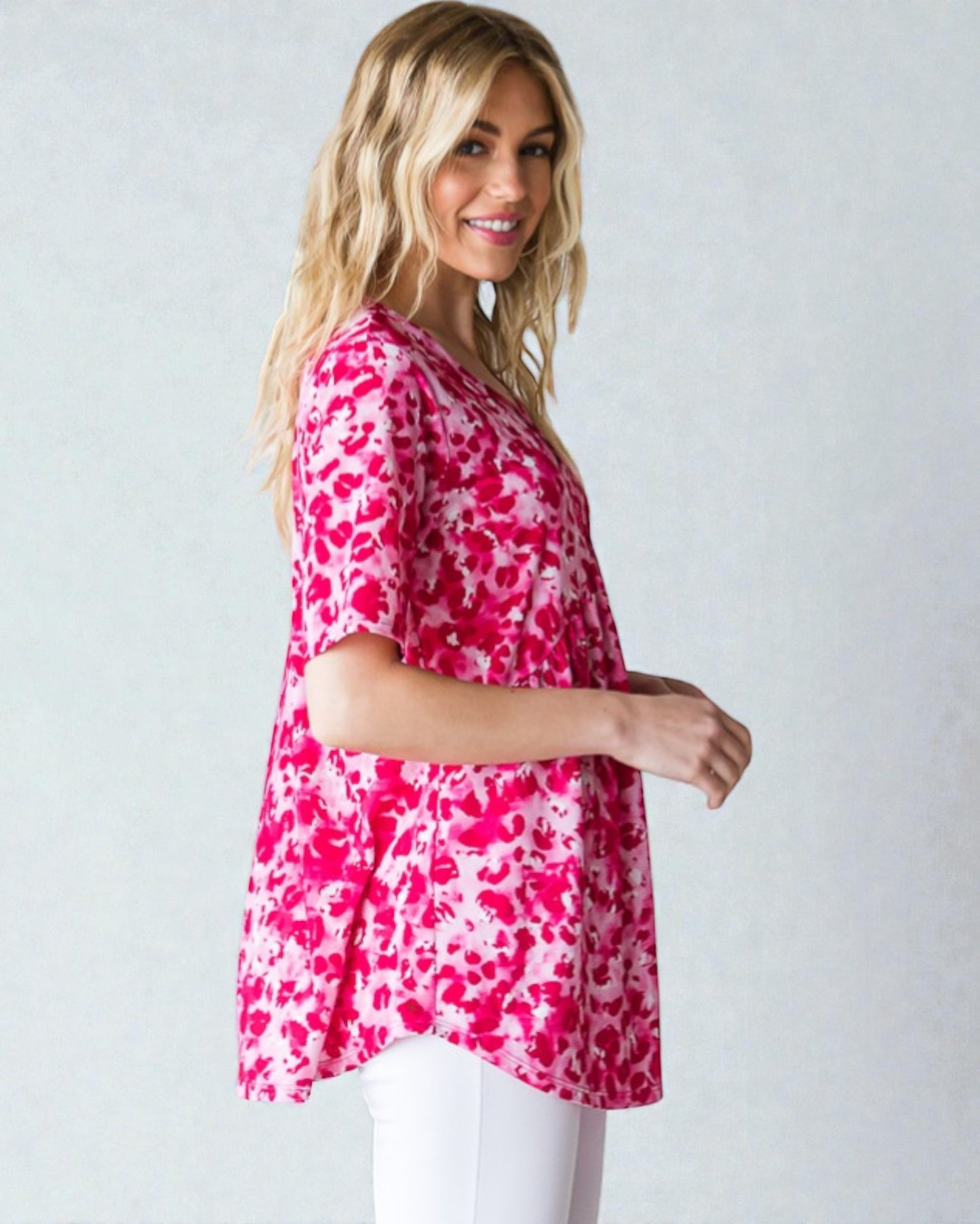 Woman wearing a pink floral tunic against a white background