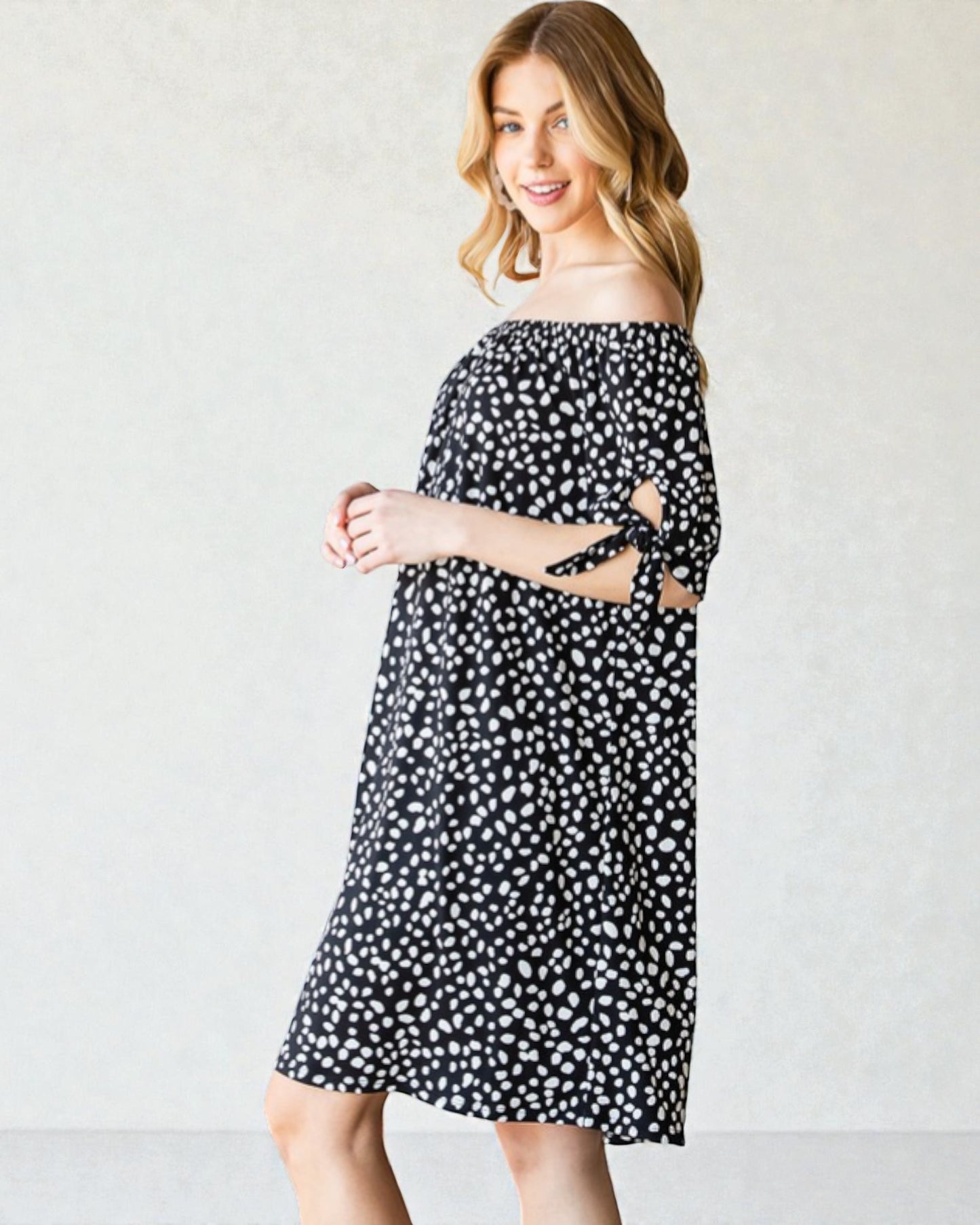 Woman wearing a black and white polka dot dress against a plain background