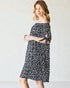 Woman wearing a black and white polka dot dress against a plain background