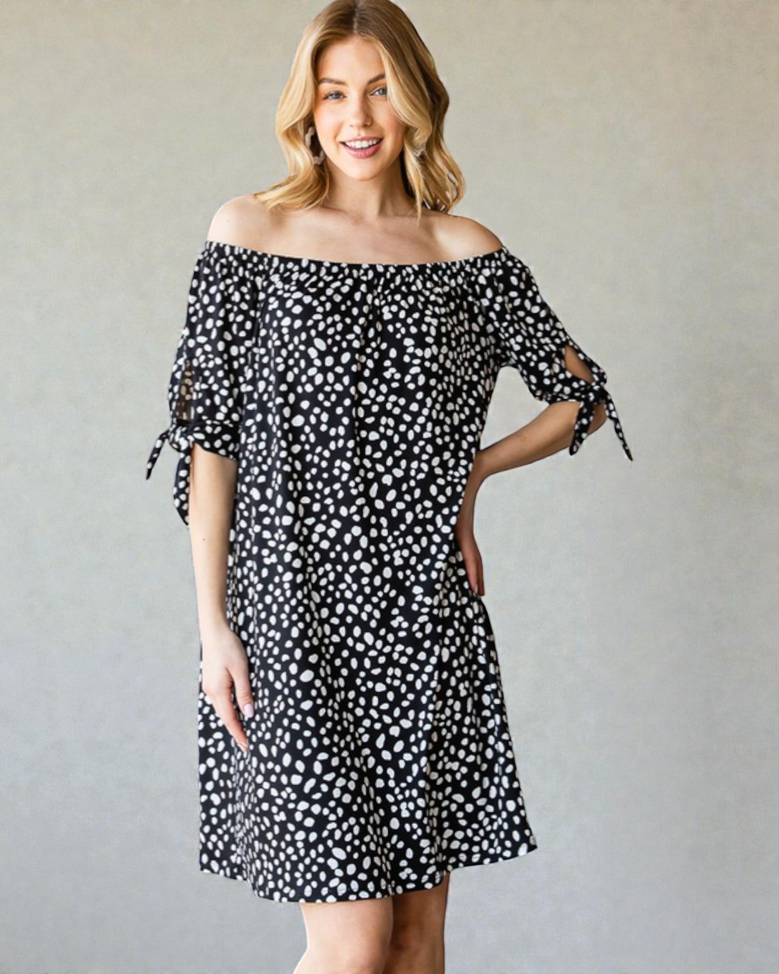 Woman wearing a black and white polka dot dress against a plain background