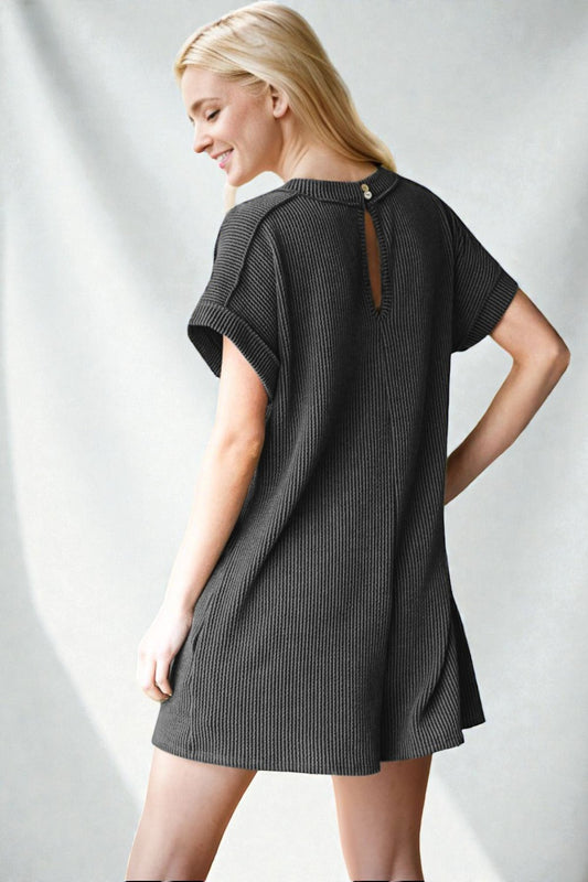 Woman wearing a dark gray dress with cut-out back design on a light gray background