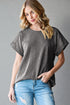 Woman wearing a gray oversized t-shirt and blue jeans against a gray background