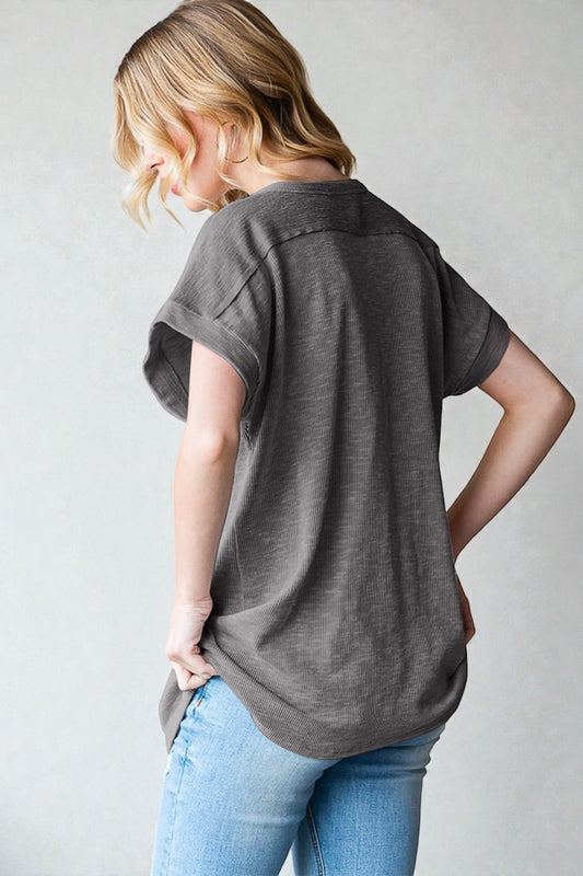 Woman wearing a gray t-shirt and blue jeans against a plain background