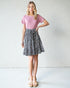 Woman wearing a pink top and patterned skirt against a plain background