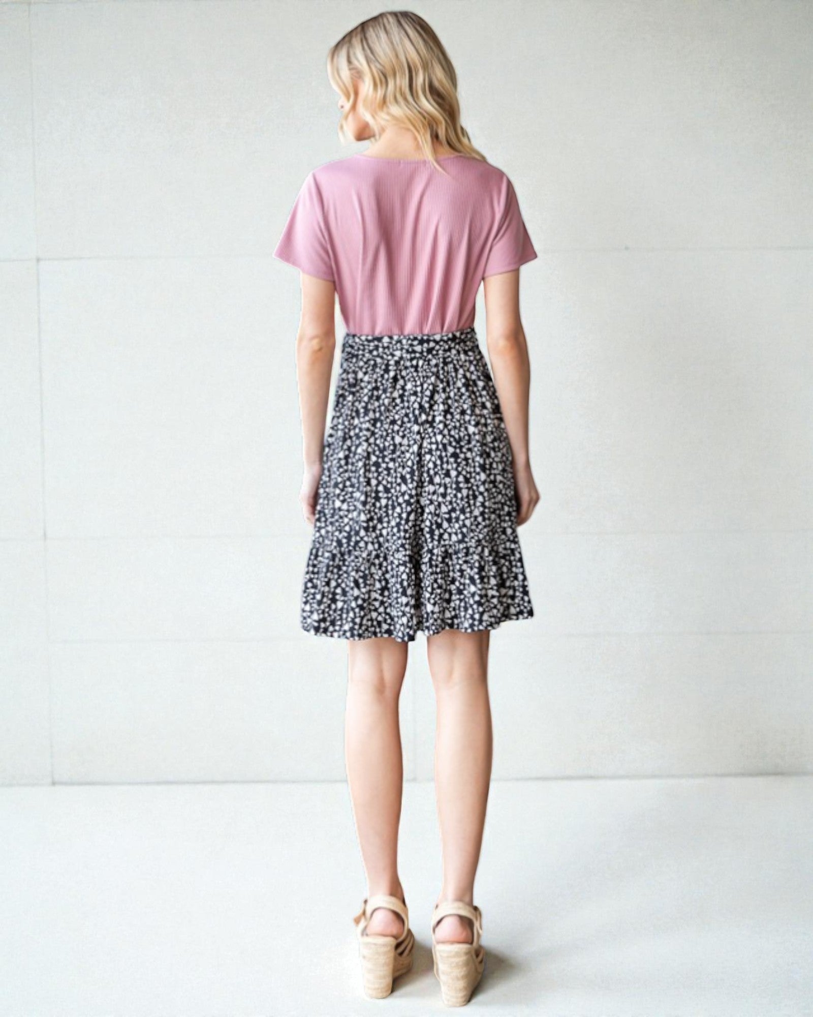 Person wearing a pink top and black and white patterned skirt on a white background