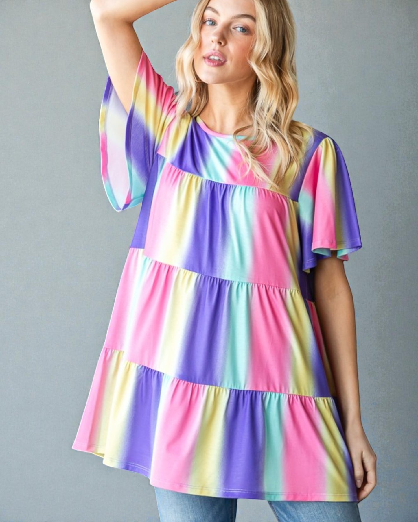Woman wearing a colorful tiered dress against a gray background