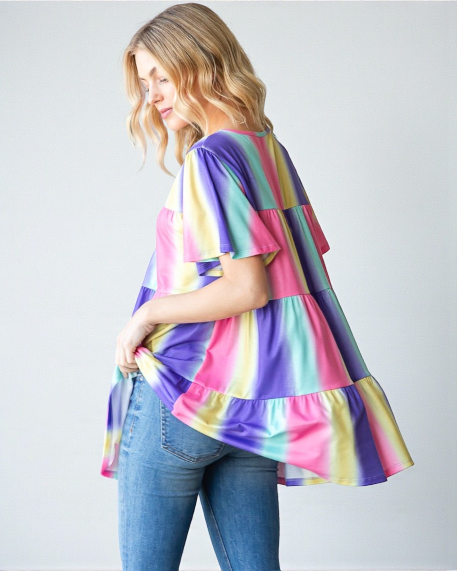 Woman wearing a colorful striped shirt and jeans on a white background