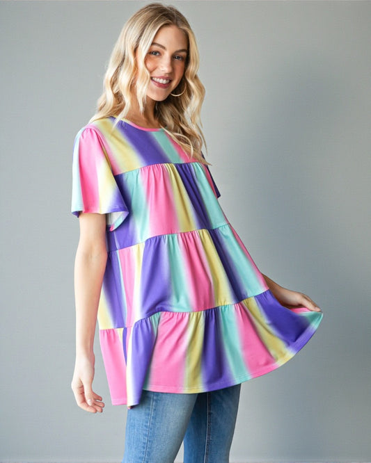 Woman wearing a colorful tiered dress against a gray background