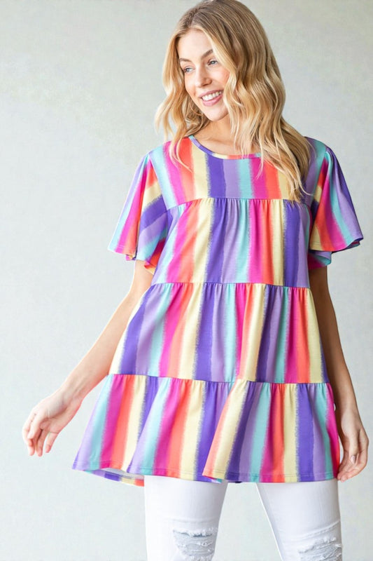Woman wearing a colorful striped dress against a plain background