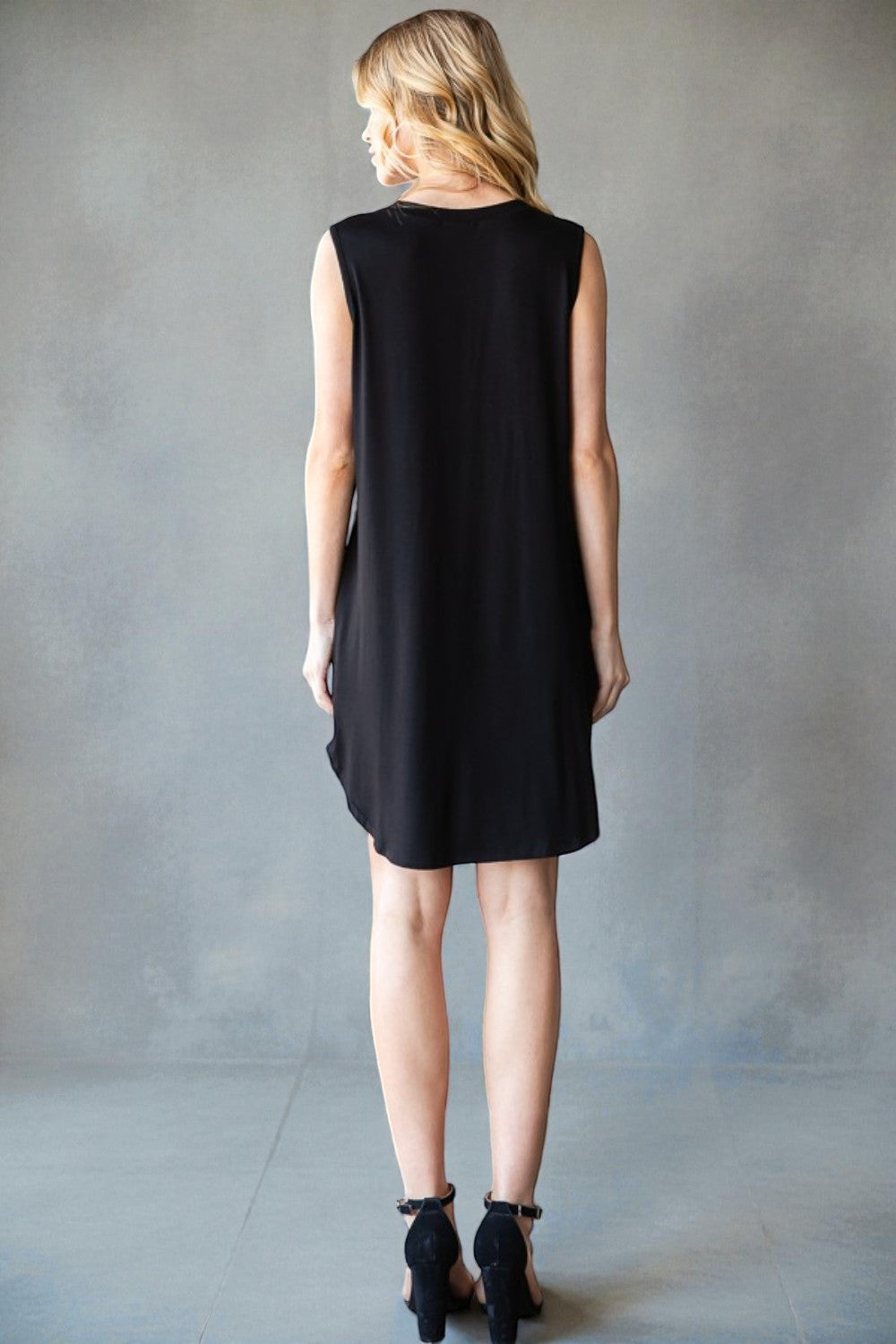 Woman wearing a black sleeveless dress against a gray background