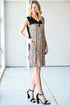 Woman wearing a leopard print dress with black accents in a minimalistic setting