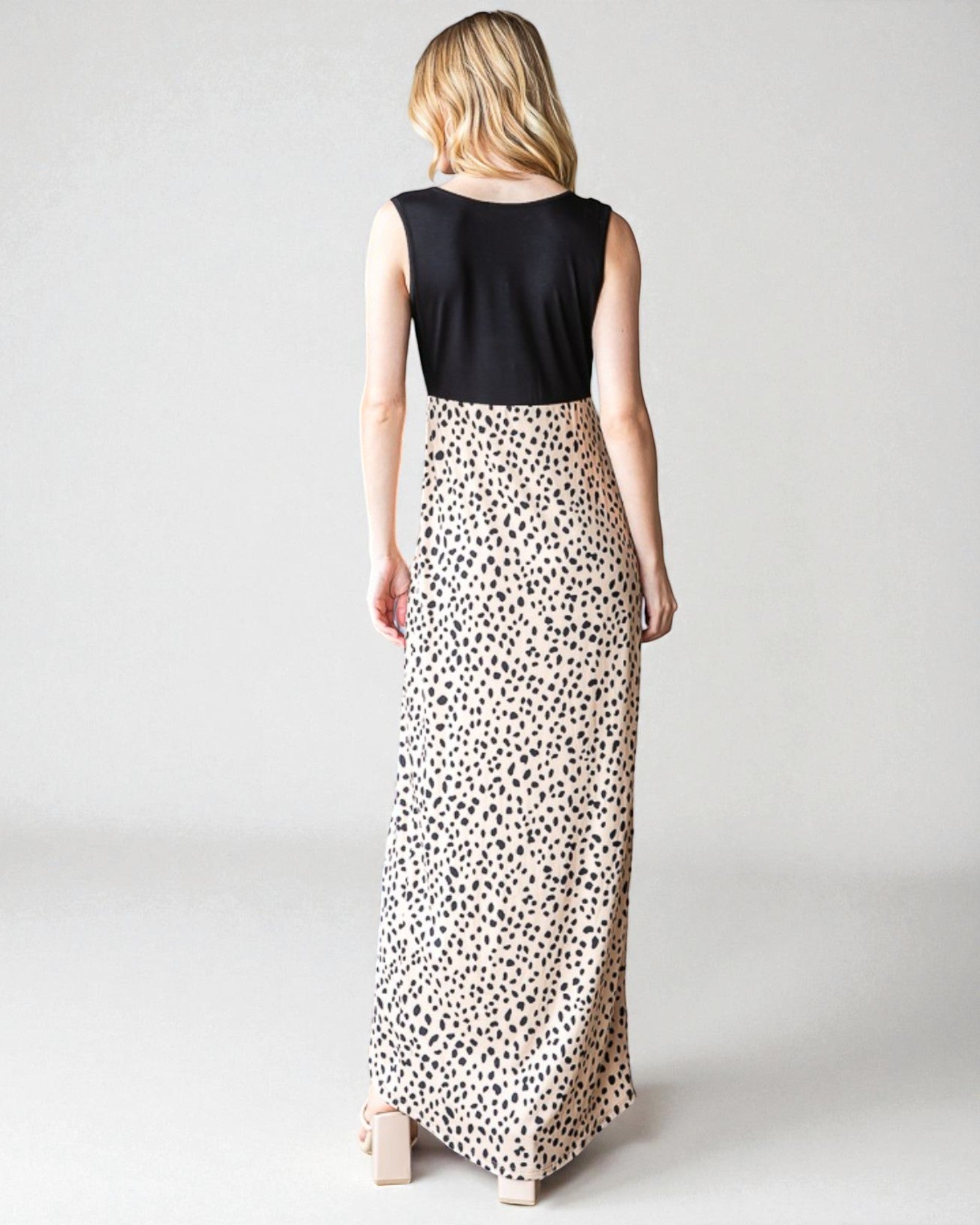 Woman wearing a black sleeveless top and leopard print skirt on a plain background