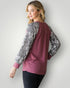 Woman wearing a maroon long-sleeve top with snake print sleeves against a white background