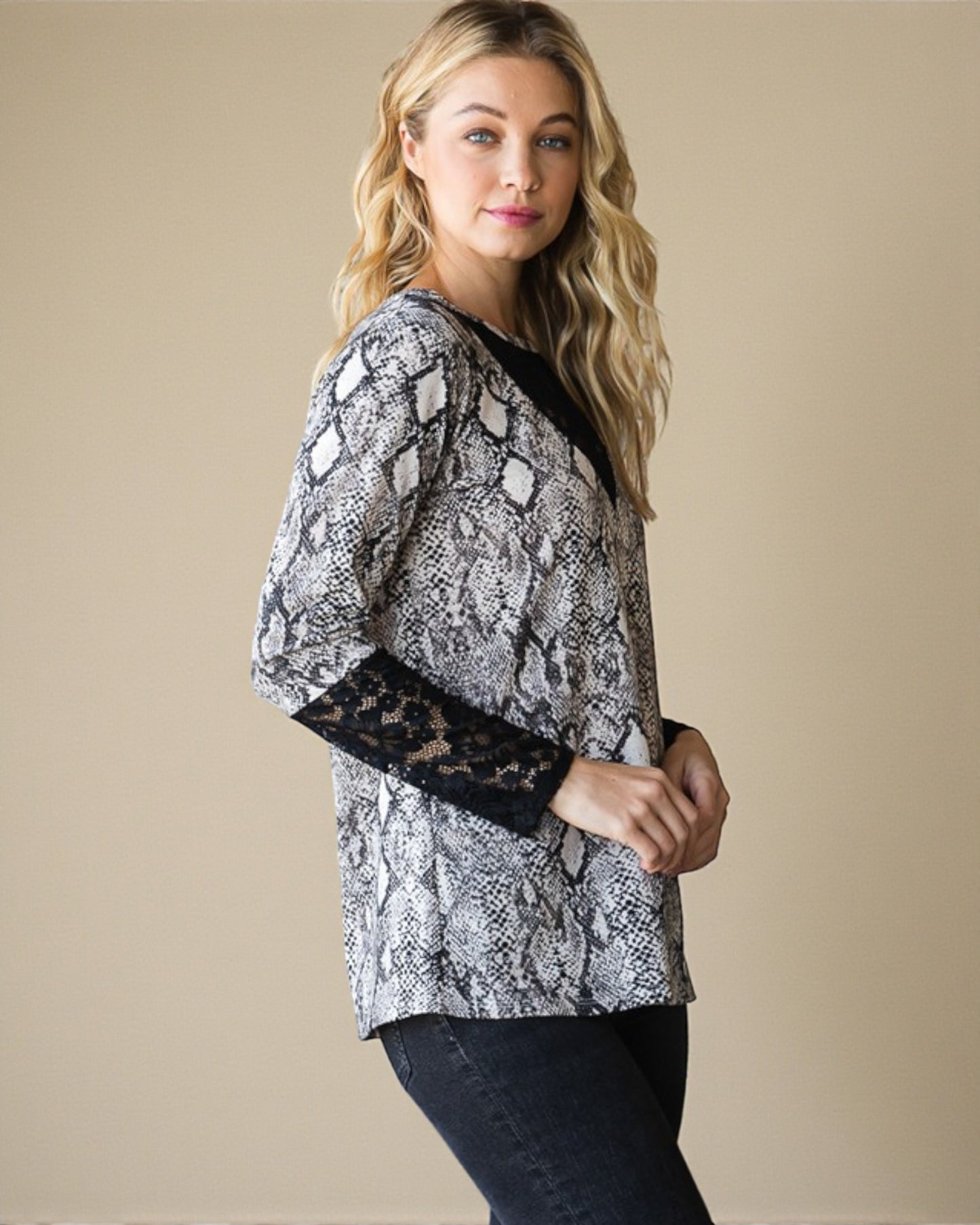Woman wearing a snake print top with lace sleeves on a beige background